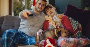 Young couple at home with their pet dog at Christmas time.